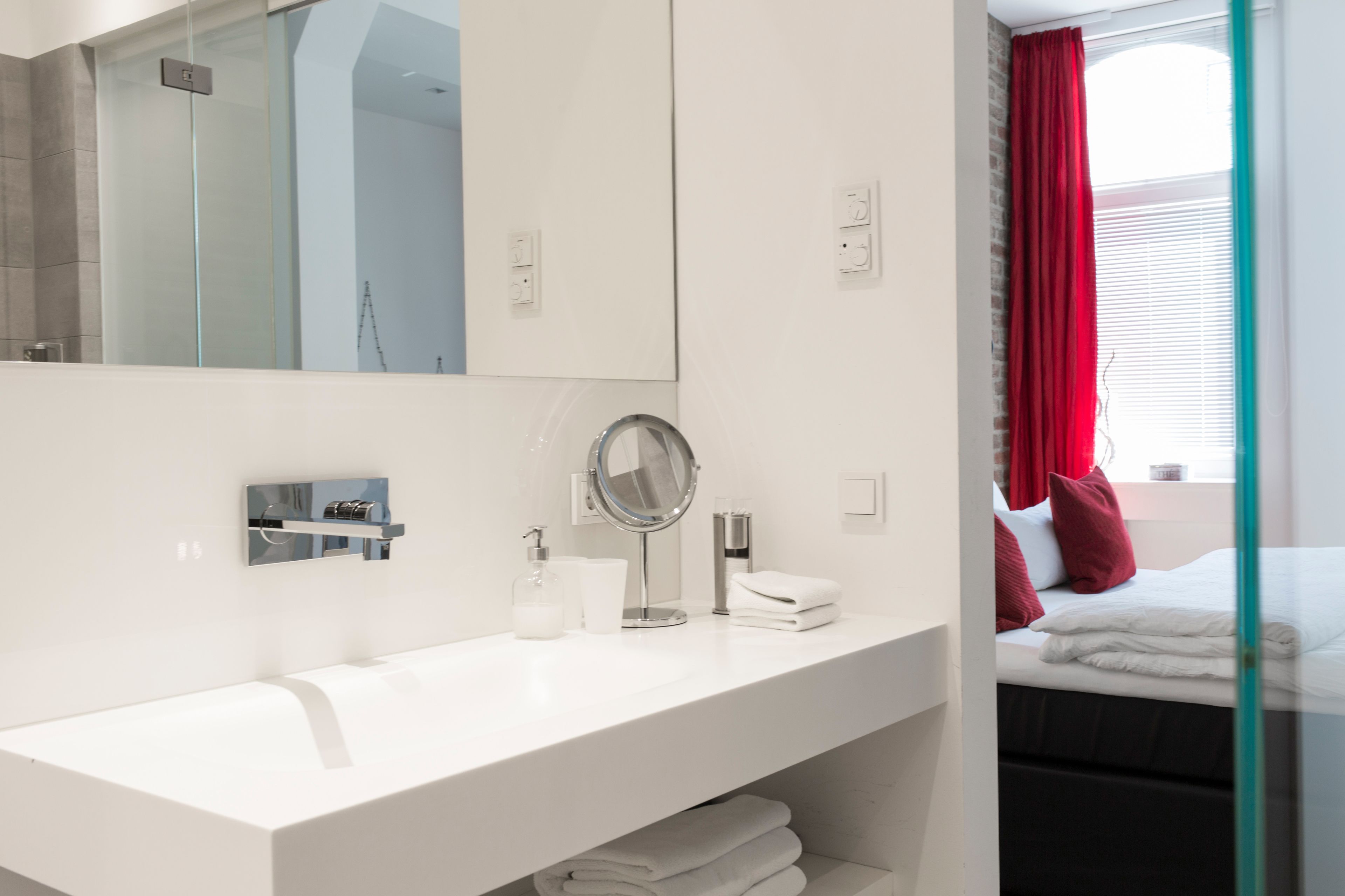 Un baño moderno con un espejo grande, lavabo blanco y cabina de ducha de vidrio.