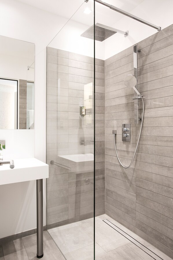 A modern bathroom with a glass-enclosed shower, a white sink, and a tiled backsplash. - 1st Floor Köln 2 (Cologne)