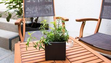 A wooden table with two chairs, a potted plant, and a staircase with a metal railing.