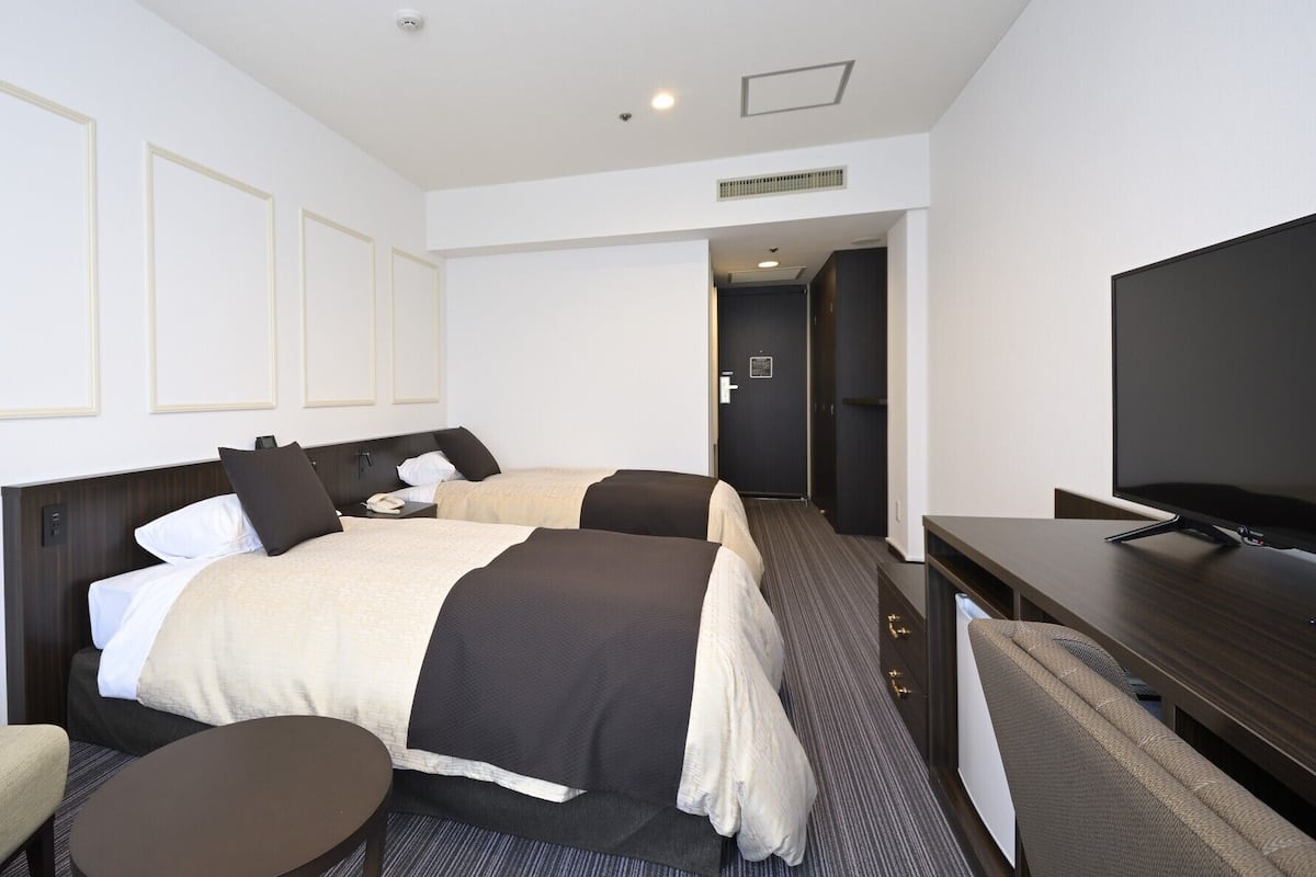 A hotel room with a bed, a TV, a desk, and a chair.