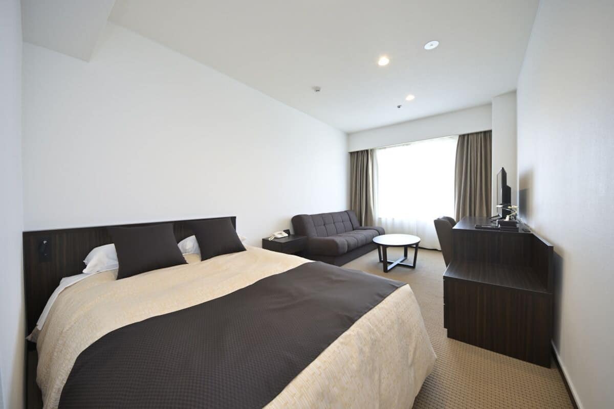 A hotel room with a large bed, a sofa, a desk, and a TV.