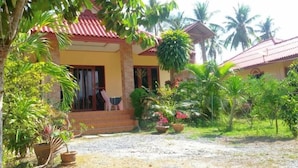 A house with a red roof, surrounded by tropical plants and palm trees. - Happy Resort (Khanom)