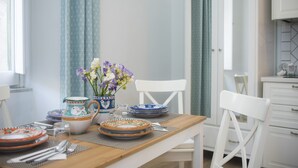 Une table à manger dressée avec des assiettes, un pichet et un vase rempli de fleurs.
