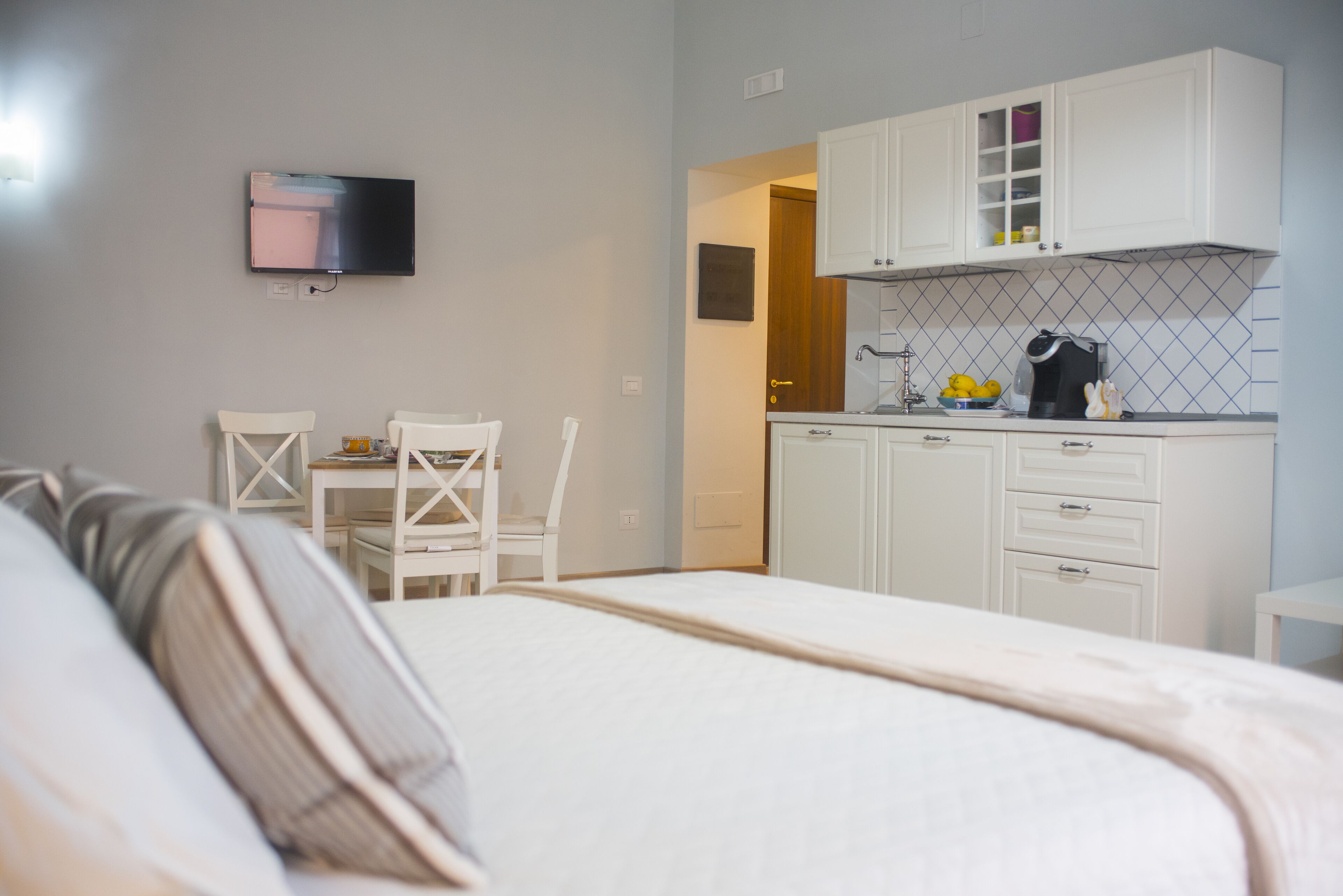 Une chambre comprenant un lit, un bureau et une kitchenette équipée de placards et d’un téléviseur.