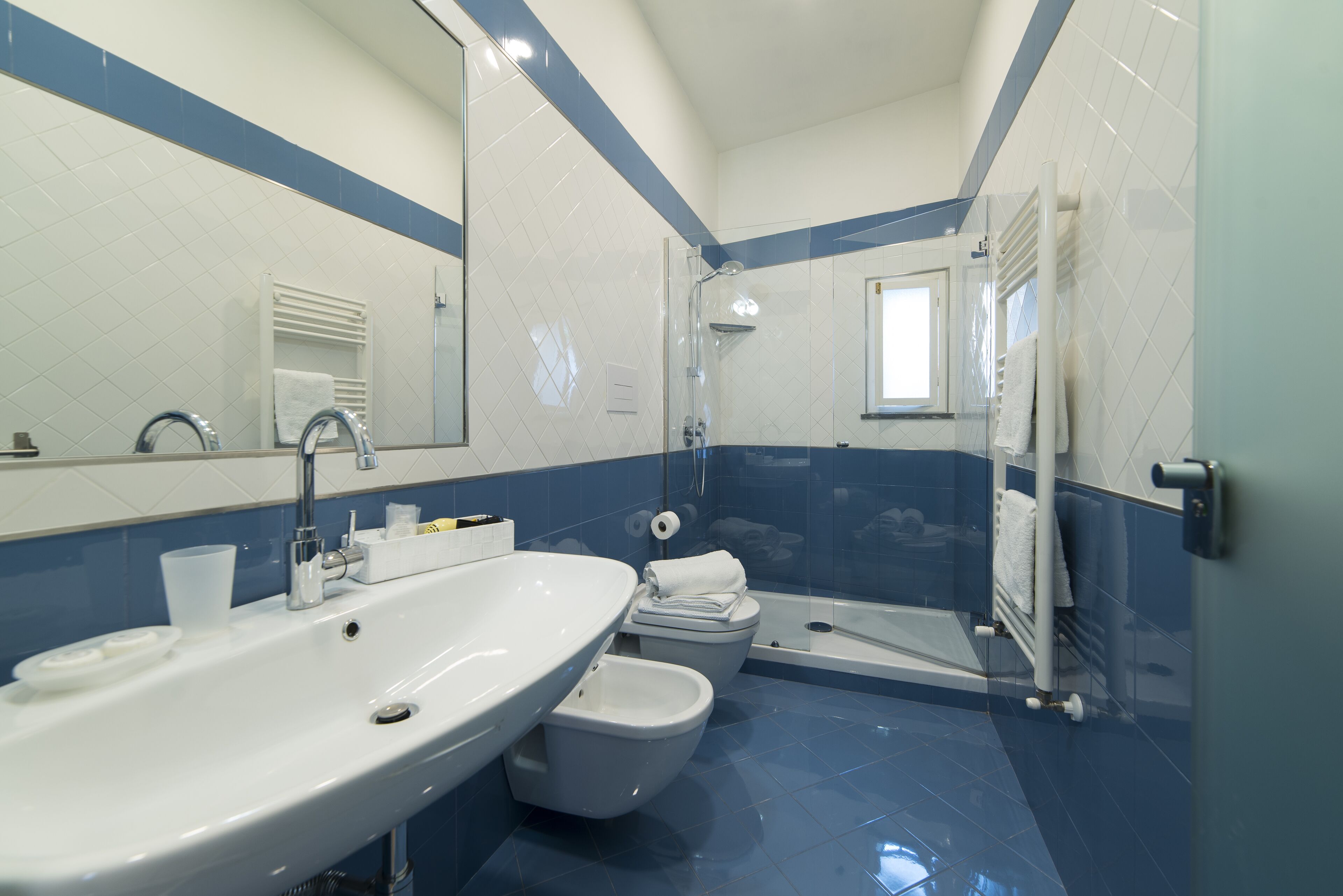 A bathroom with a sink, toilet, bidet, and glass-enclosed shower.