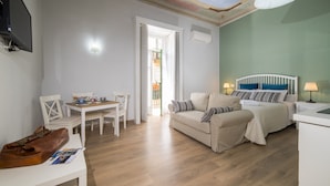 Une pièce de taille modeste comprenant un lit, un canapé, une table à manger avec des chaises et un téléviseur fixé au mur.