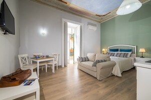 Una habitación compacta con cama, sofá, mesa de comedor con sillas y televisión fijada a la pared.