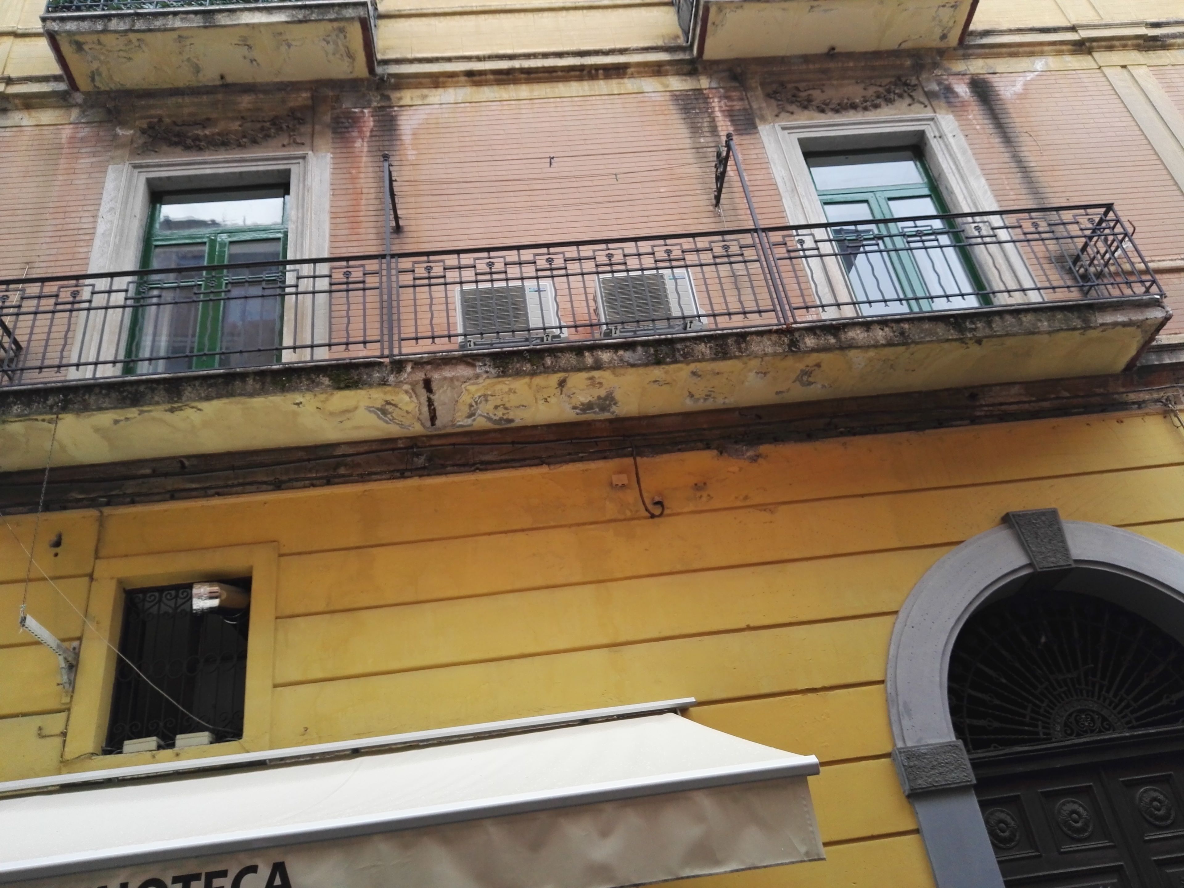 Un bâtiment jaune doté d’un balcon et d’une porte surmontée d’une arche décorative.