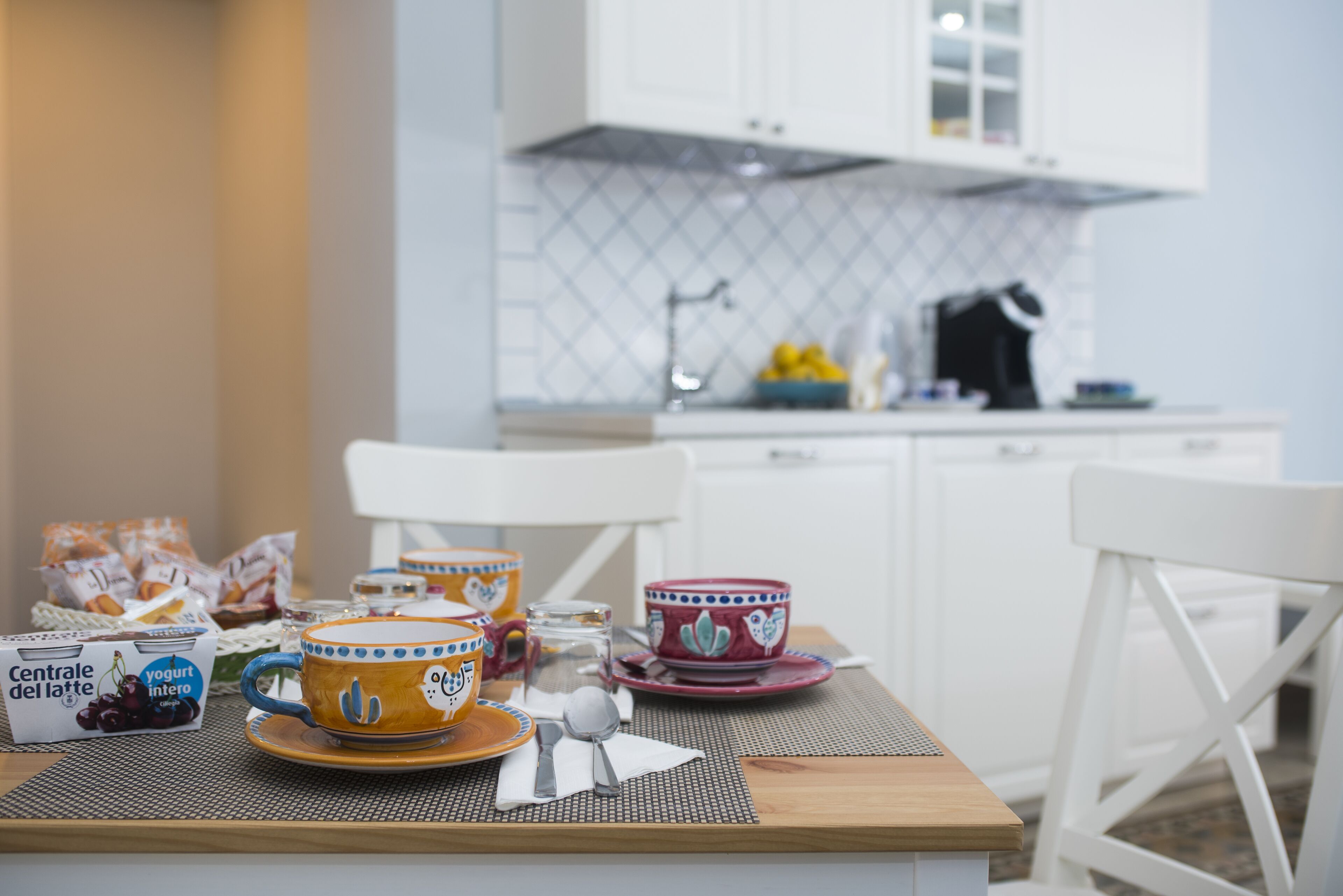A breakfast table set with cups, a jug, and a box of yogurt.