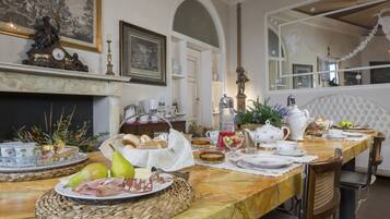 A dining area with a marble table set for breakfast, including bread, pastries, and fruit.
