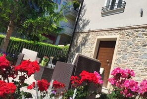 Un patio con mobiliario exterior, un edificio de piedra y una puerta de madera.