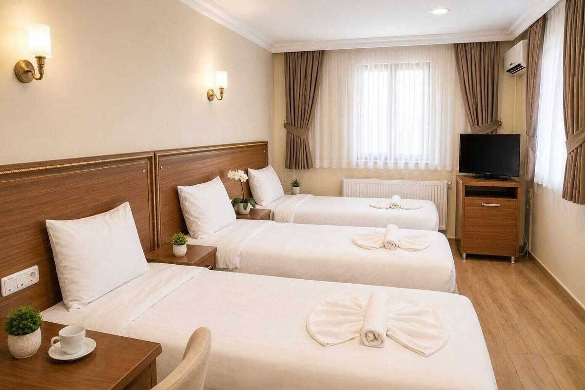 A hotel room with two beds, a TV, a dresser, and a window with curtains.