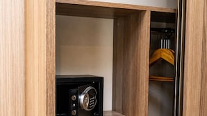 Un armario de madera con un dispositivo electrónico negro en un estante, un perchero y un par de zapatillas blancas.
