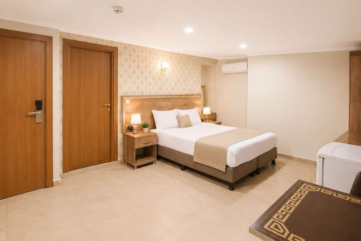 A hotel room with a bed, bedside tables, a desk, and a chair.