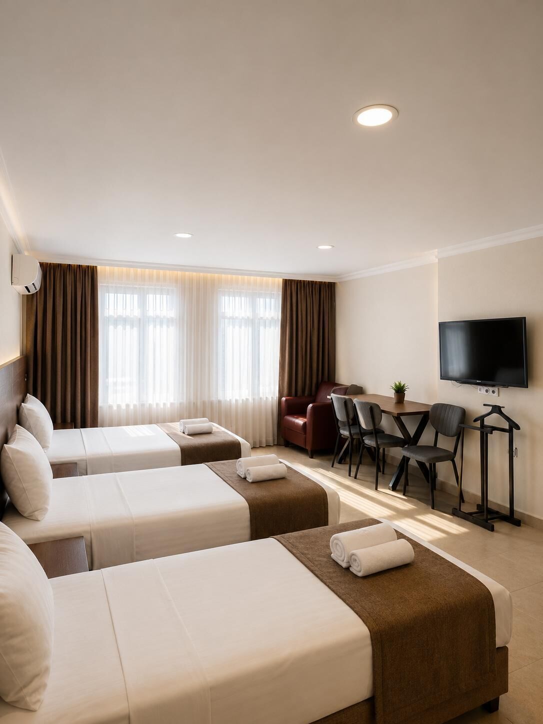 A hotel room with two beds, a desk, a TV, and a chair.