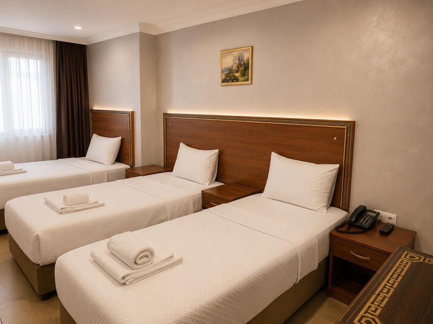 A hotel room with two beds, a nightstand with a phone, and a painting on the wall.