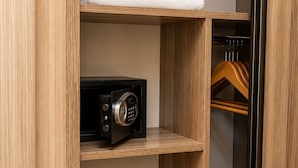 Un armario de madera con repisas que guardan toallas dobladas, un dispositivo electrónico negro y un par de pantuflas.