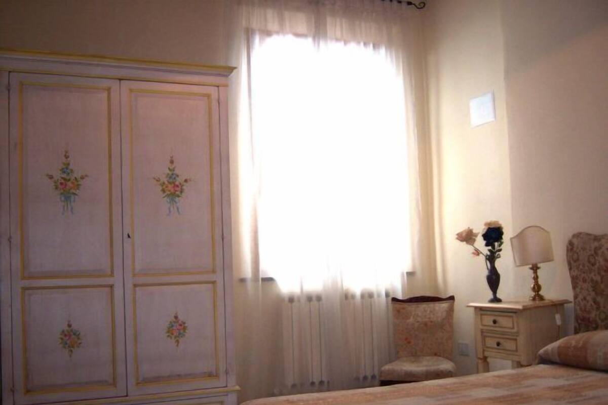 A bedroom with a large wardrobe, a bedside table with a lamp, and a floral-patterned bedspread.