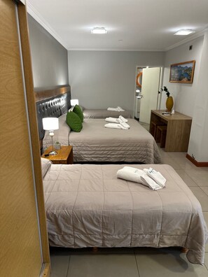 Une chambre d’hôtel avec deux lits, une table de chevet avec une lampe, une petite plante et un tableau au mur.