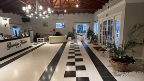 Un vestíbulo de hotel con piso a cuadros, una mesa de recepción y una araña.