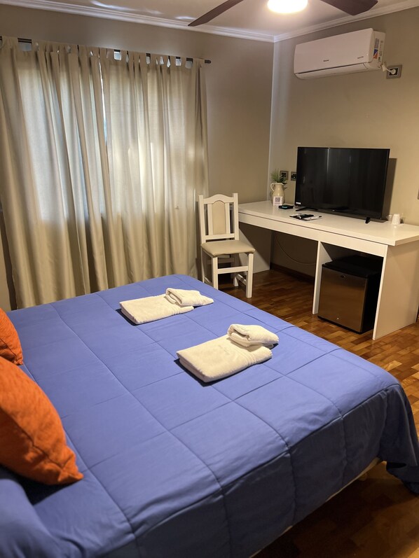 Une chambre comprenant un lit, un bureau, une chaise, un téléviseur et un appareil de climatisation.