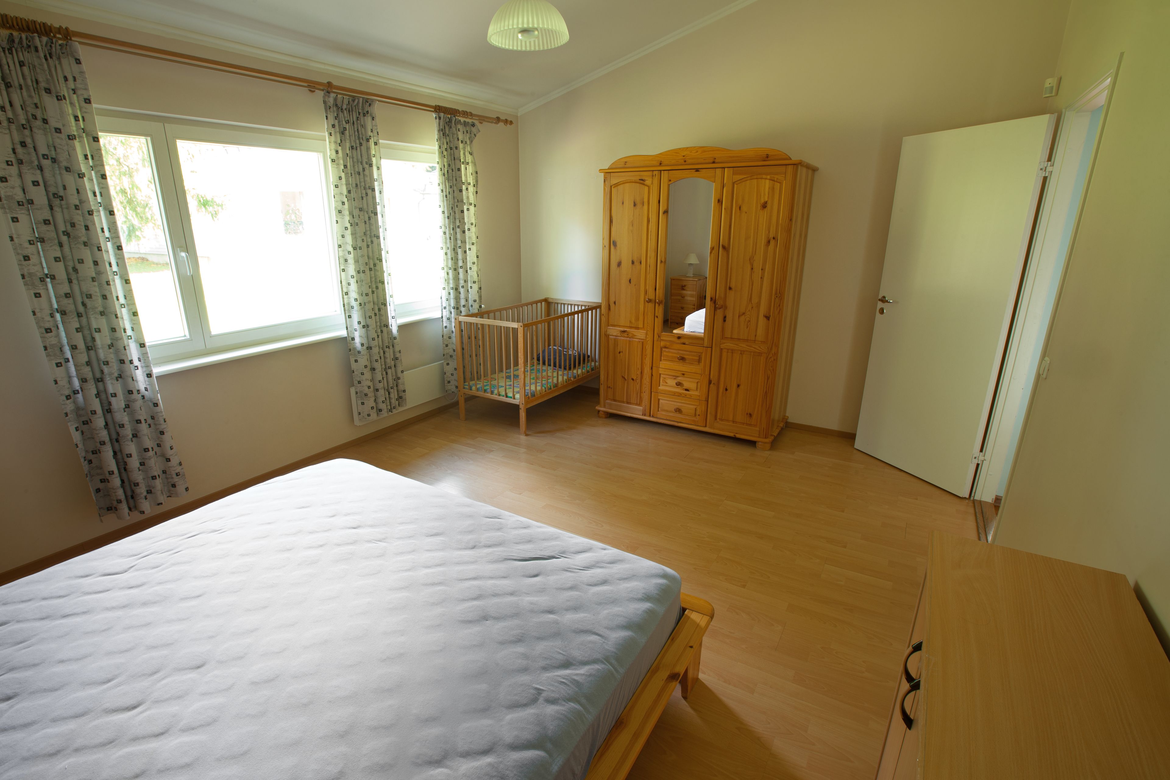 Une chambre à coucher avec un grand lit, une armoire en bois et un berceau.