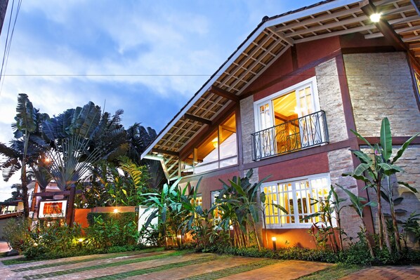A two-story house with a balcony, surrounded by lush greenery and a well-maintained garden. - Pousada Terra Juquehy (São Sebastião)