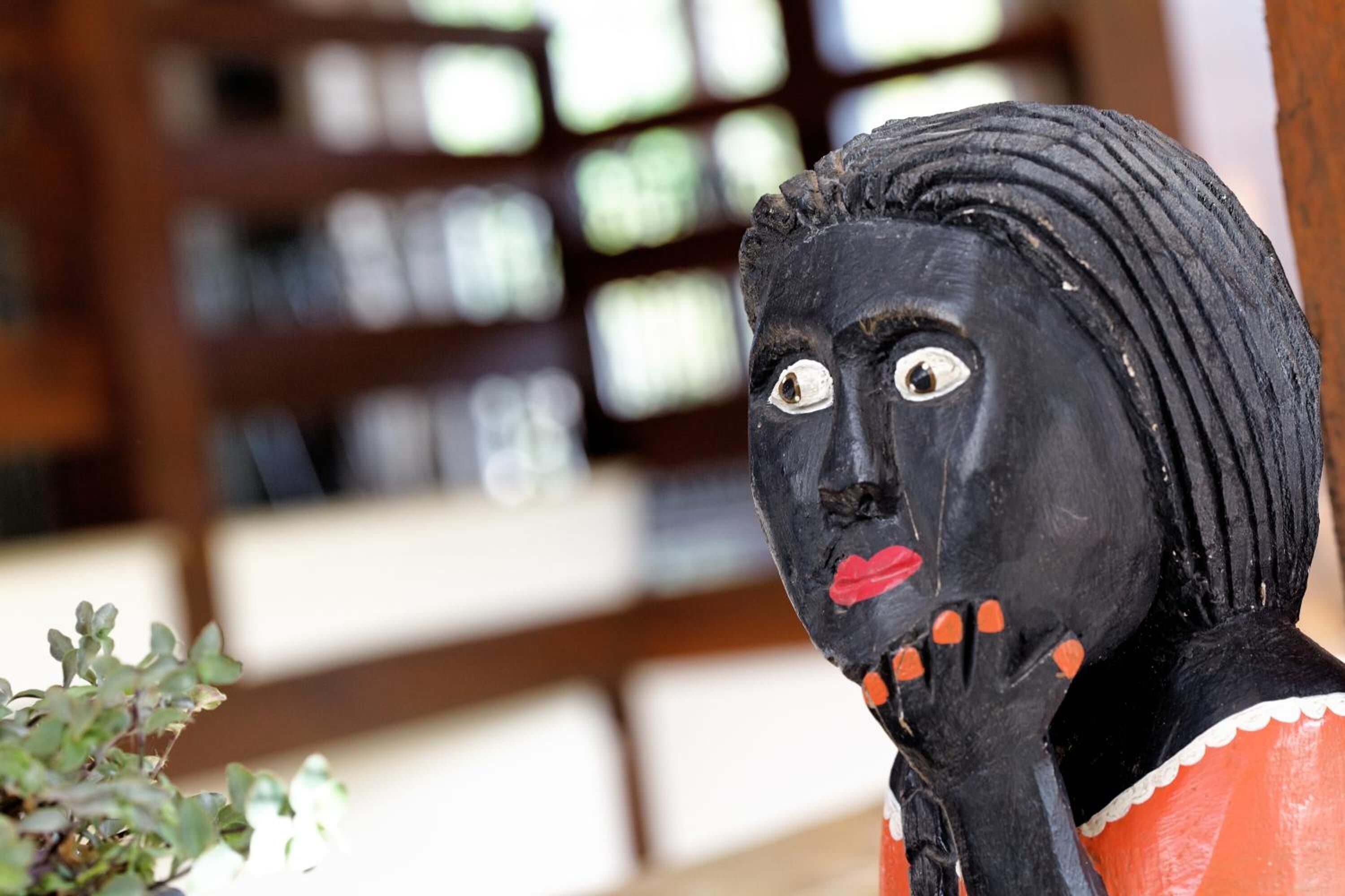 A sculpture with a black face, red lips, and orange accents.