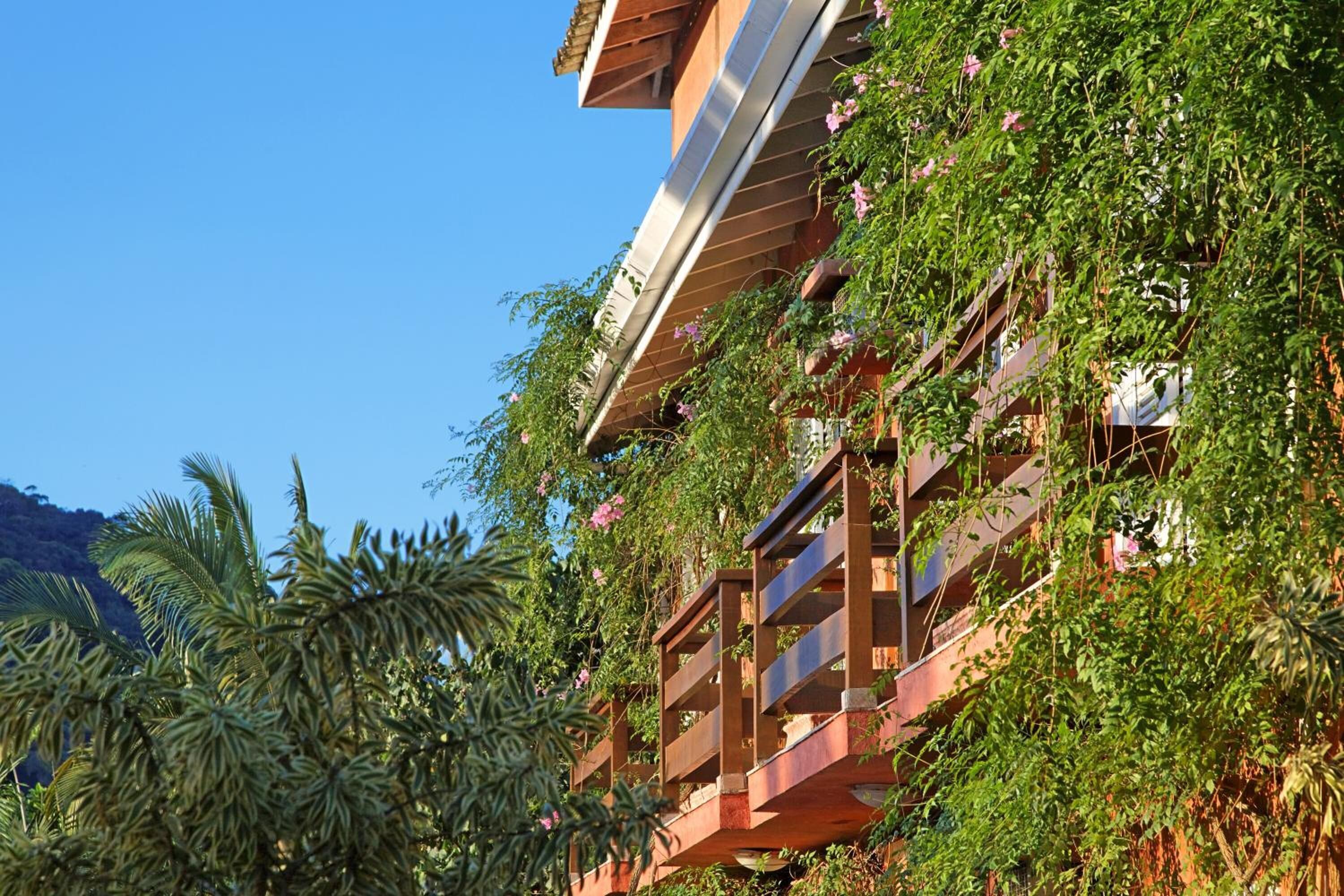 A multi-story building with balconies covered in greenery and flowers.