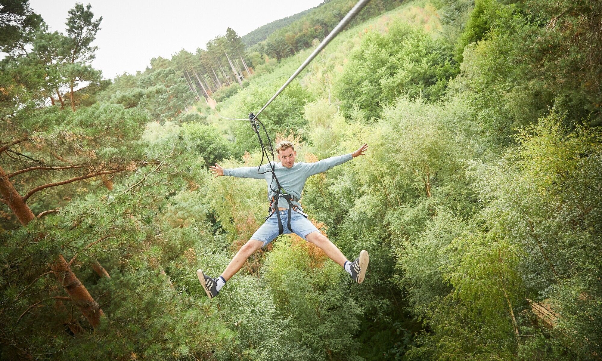 Una persona haciendo bungee jumping desde un punto elevado rodeado de abundante follaje verde.