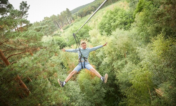 Une personne pratiquant le saut à l’élastique depuis un point élevé, entourée d’une végétation luxuriante.