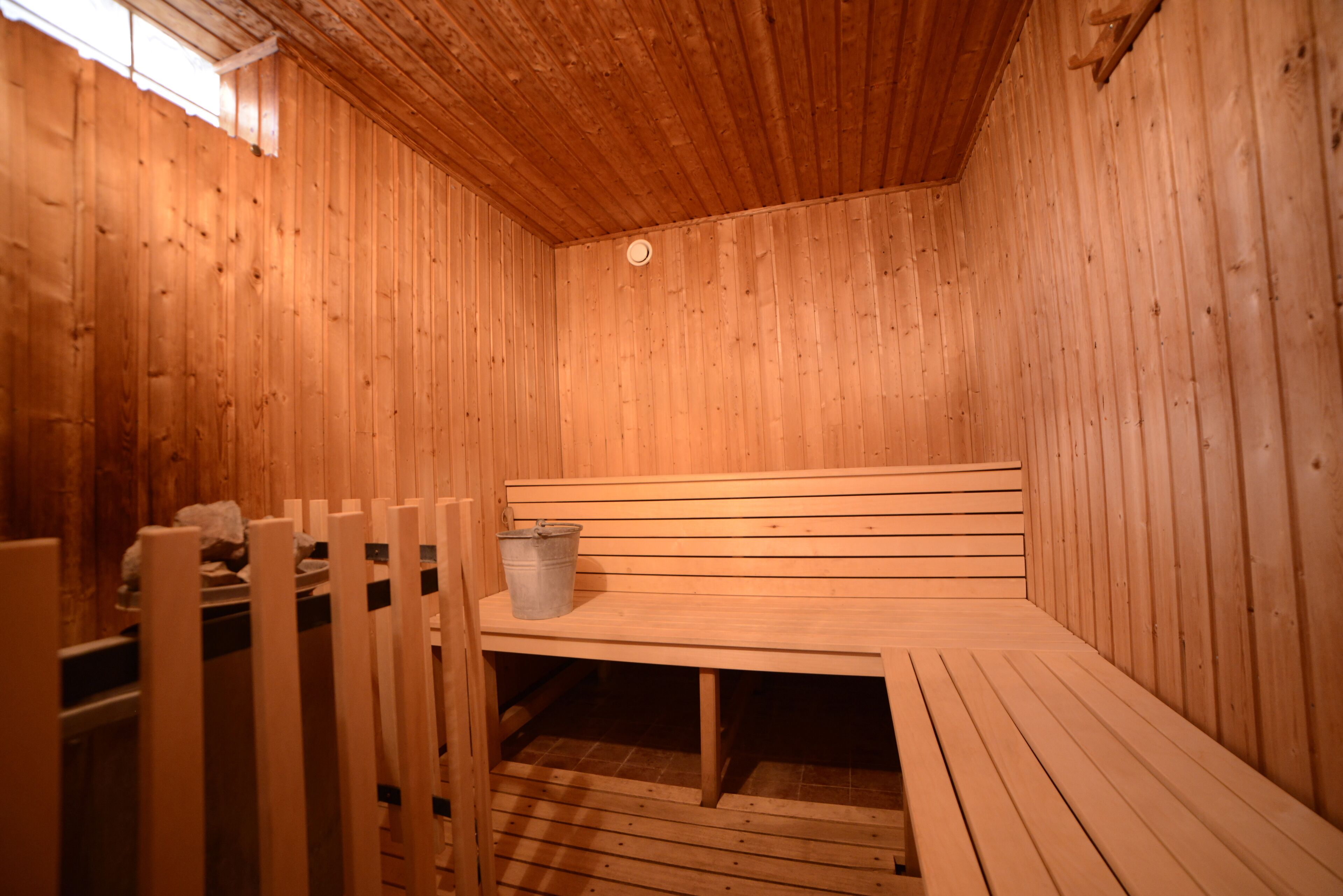 Uma sauna de madeira com bancos e um balde.