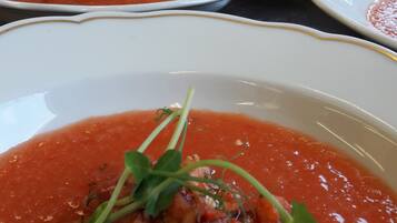 Una fila de platos blancos con salsa roja y adornados con hierbas verdes.