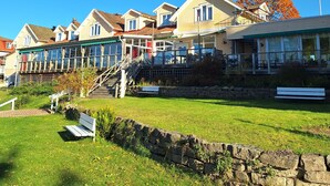Una hilera de casas con jardín delantero de césped, muro de piedra y un banco.