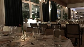 Comedor con mesas dispuestas para una comida, con vasos transparentes, platos y cubiertos.