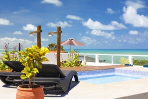 A poolside area with lounge chairs, a potted plant, and a view of the ocean. - Pipa Centro Residence (Tibau do Sul)