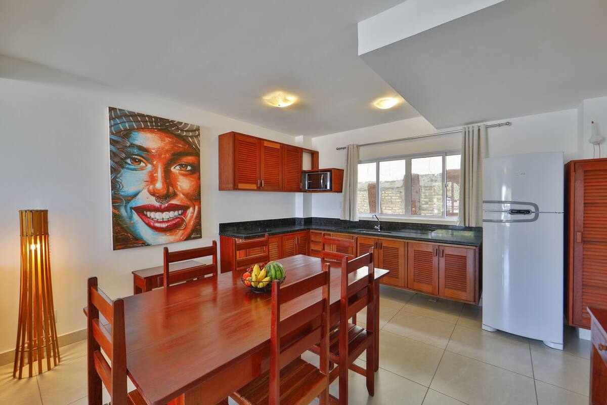 A modern kitchen with wooden cabinets, a dining table, and a refrigerator.