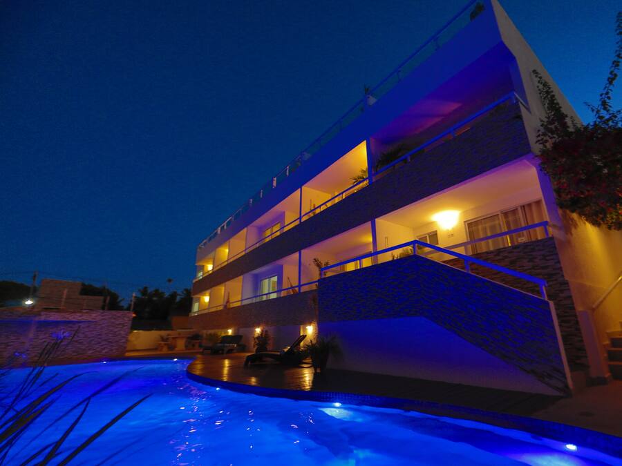 A multi-story hotel with a swimming pool at the ground level.