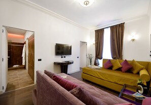 A living room with a sofa, a television, and a window with curtains. - Suites Rome Condotti (Rome)