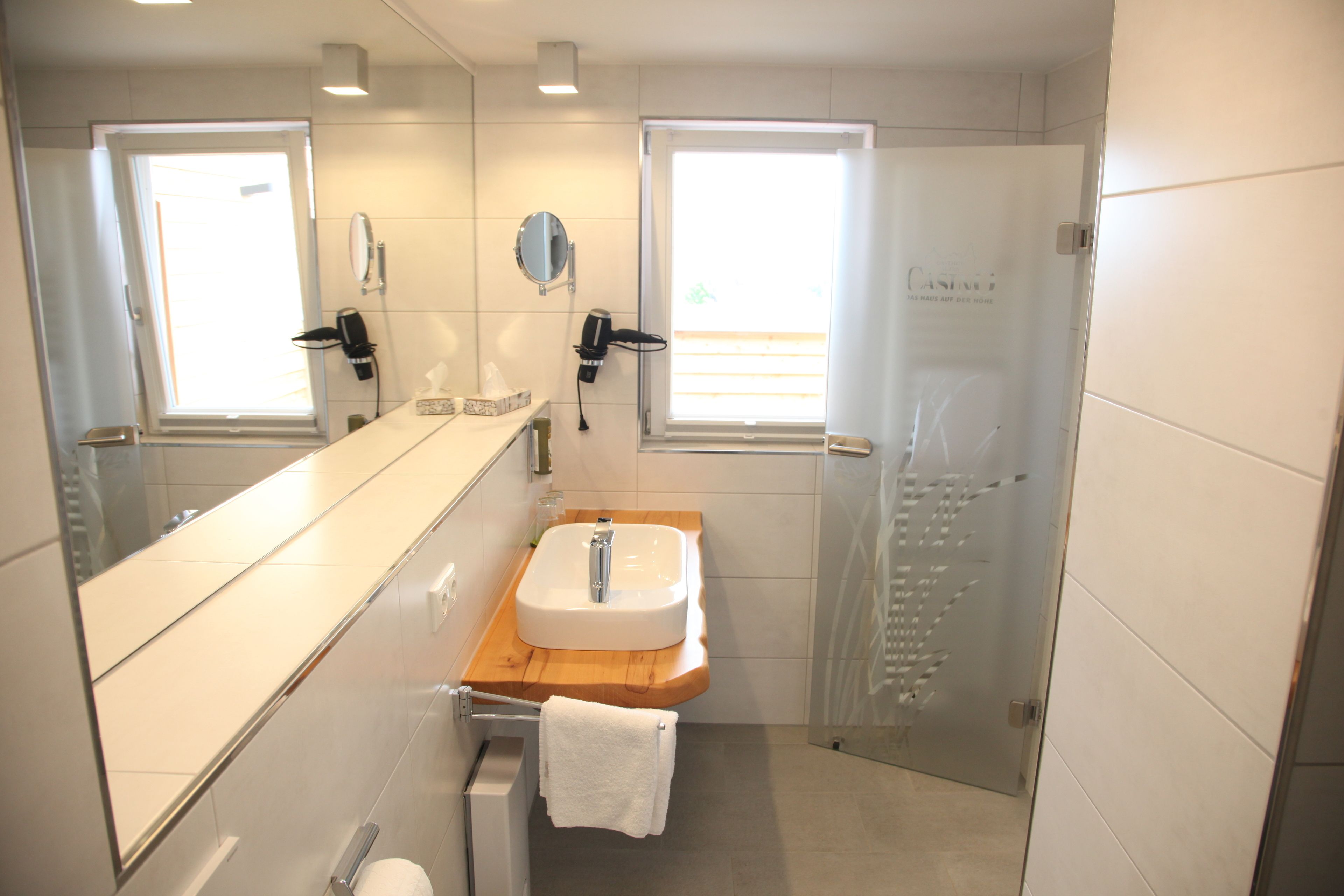 Un bagno moderno con uno specchio grande, un lavandino e una doccia.