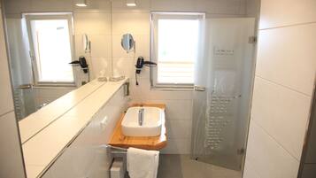 Un bagno moderno con uno specchio grande, un lavandino e una doccia.
