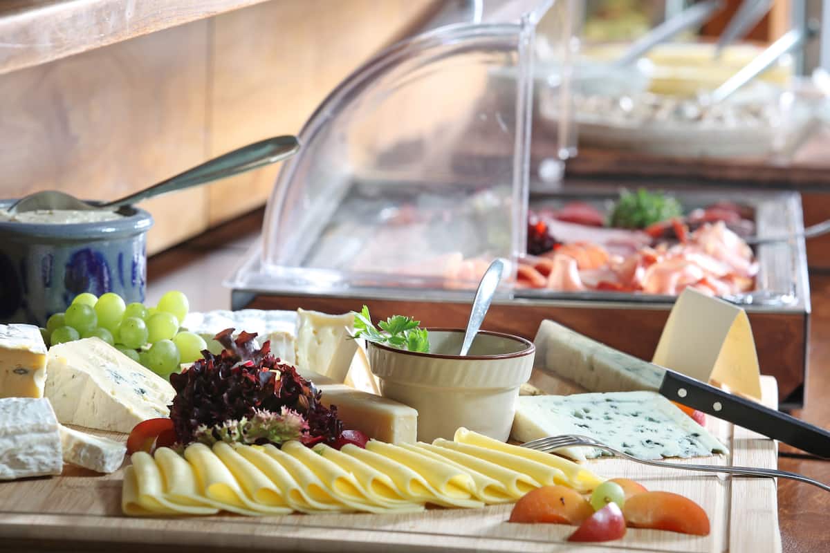 A buffet with various cheeses, fruits, and vegetables.