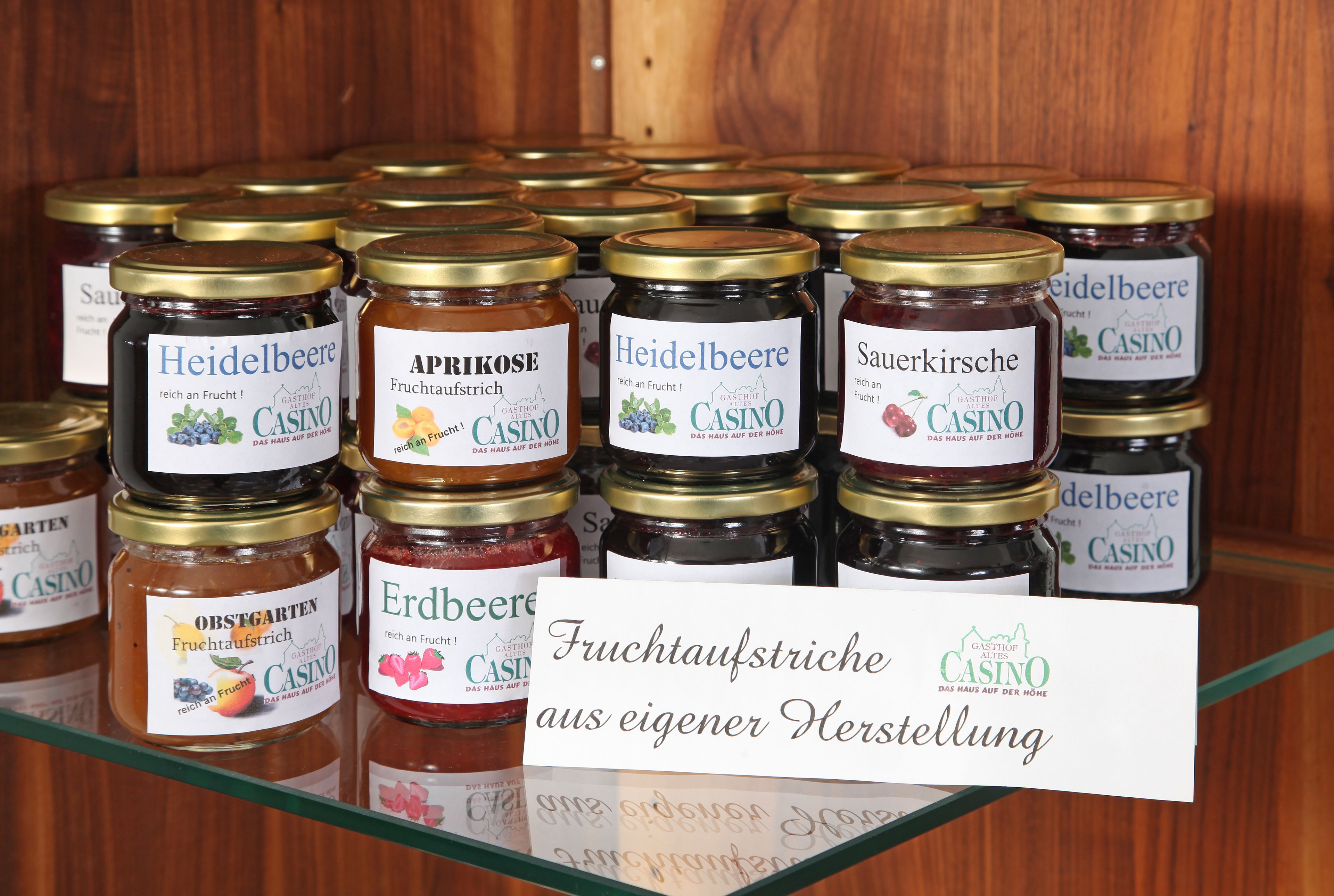 A display of various fruit preserves in jars with labels, including names and types of fruits.