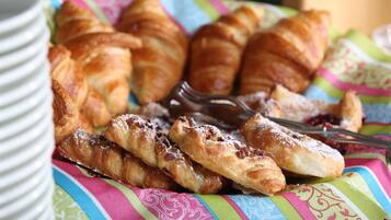 A plate of croissants and pastries with a fork on a colorful tablecloth.