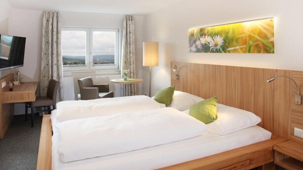 Een hotelkamer met twee bedden, een bureau, een stoel, een televisie en een raam met uitzicht.