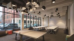 A modern conference room with a ping pong table, multiple tables, and chairs arranged for meetings. - Radisson RED Minneapolis Downtown (Minneapolis)