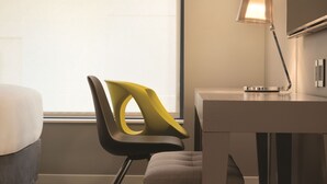 Una habitación de hotel moderna con escritorio, silla y lámpara.