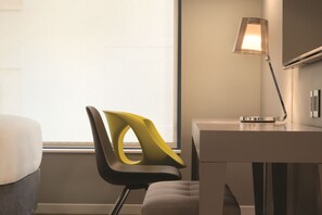 Una habitación de hotel moderna con escritorio, silla y lámpara.