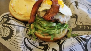 Un sándwich de tocino, huevo y lechuga sobre un papel estampado.