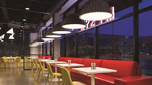 A modern restaurant with yellow chairs, red booths, and pendant lights. - Radisson RED Minneapolis Downtown (Minneapolis)